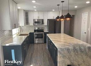 Denver house for rent - a kitchen with white cabinets and a marble counter top