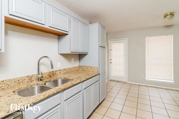 Fort Worth house for rent - a kitchen with white cabinets and a granite counter top and a sink