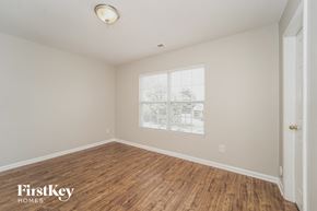 Matthews house for rent - A room with wooden flooring and a window showing a view of trees and buildings outside.