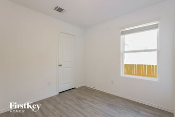 San Antonio house for rent - a bedroom with white walls and a window and wooden floors