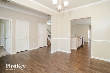 Canton house for rent - A spacious room with wooden floors and white walls, featuring a chandelier and a kitchen area in the distance.