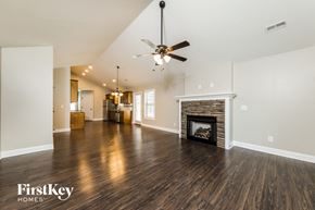Kernersville house for rent - A spacious living room with a fireplace and a ceiling fan.