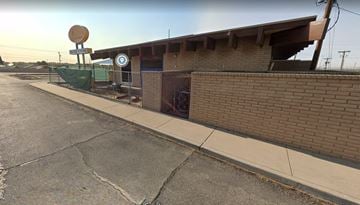 El Paso apartment for rent - A building with a satellite dish on top and a sign with a white background and a blue border with a white circle and a white arrow pointing to the right.