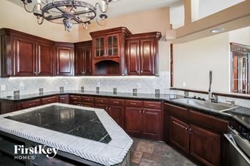 Edmond house for rent - a kitchen with dark wood cabinets and black countertops and a black and white island