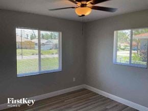 Fort Myers house for rent - an empty bedroom with a ceiling fan and two windows