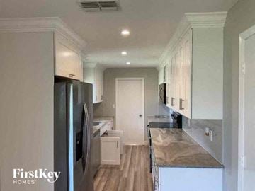 Fort Myers house for rent - a kitchen with white cabinets and a stainless steel refrigerator