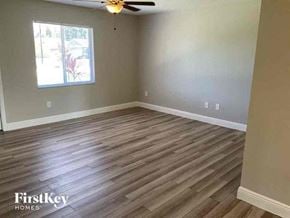 Fort Myers house for rent - a empty living room with wood floors and a ceiling fan