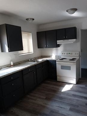 Jennings apartment for rent - an empty kitchen with black cabinets and a white stove
