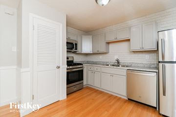 St Louis house for rent - a kitchen with white cabinets and stainless steel appliances