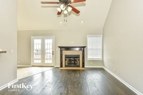 Clarksville house for rent - A spacious living room with a fireplace and a ceiling fan.