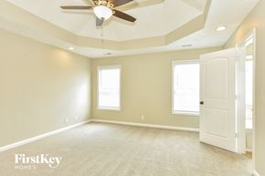 Clarksville house for rent - A spacious room with a ceiling fan and a door on the right side.
