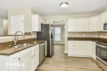 Hermitage house for rent - a kitchen with white cabinets and granite counter tops