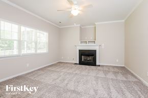 Moncks Corner house for rent - a empty living room with a fireplace and a ceiling fan