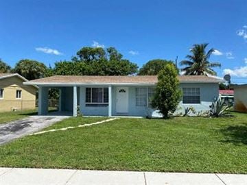 Fort Lauderdale house for rent - a blue house with a lawn and a palm tree