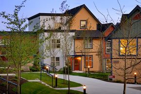 Nanaimo apartment for rent - A building with a white door and windows is lit up at dusk.