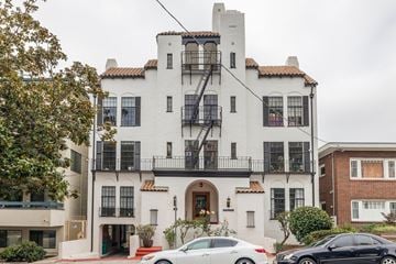 Oakland apartment for rent - A white building with a black balcony and a car parked in front.