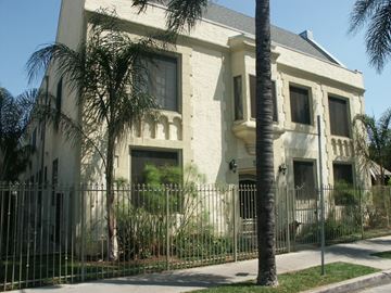 Los Angeles apartment for rent - A white building with a black fence and a palm tree in front.