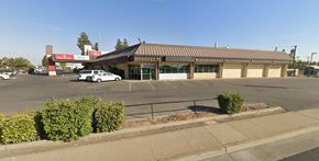 Sacramento apartment for rent - A parking lot with a building in the background and a car parked in the lot.