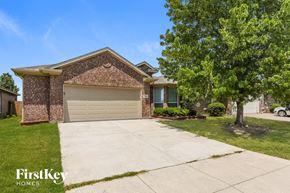 Fort Worth house for rent - A brick house with a garage door and a tree in front.