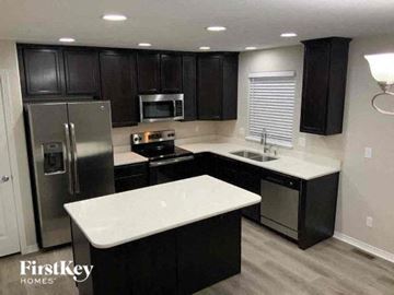 Colorado Springs house for rent - a kitchen with black cabinets and a stainless steel refrigerator
