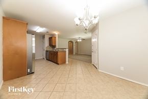 Denton house for rent - A spacious room with a chandelier and a kitchen area in the background.