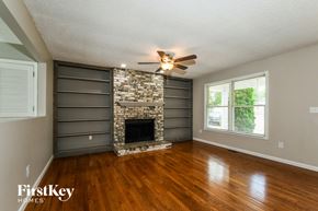 St. Louis house for rent - an empty living room with a fireplace and a ceiling fan