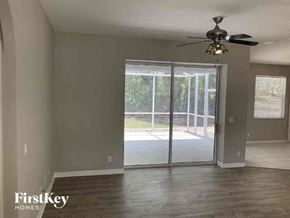 North Port house for rent - an empty living room with a ceiling fan and sliding glass doors