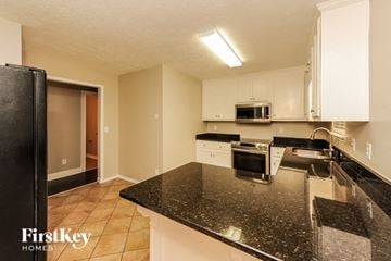 Gainesville house for rent - a kitchen with black granite counter tops and white cabinets