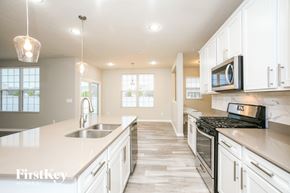 Whitestown house for rent - a kitchen with white cabinets and a sink and a stove