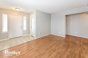 Cypress house for rent - the living room and dining room with wood flooring and a white door