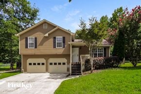 Dallas house for rent - a tan house with two garage doors and a driveway
