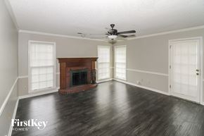 Collierville house for rent - an empty living room with a fireplace and a ceiling fan