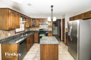 Collierville house for rent - a kitchen with wooden cabinets and stainless steel appliances and marble counter tops