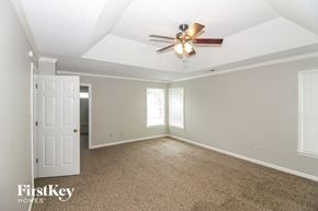 Collierville house for rent - an empty living room with a ceiling fan and a white door