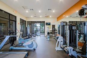 Chandler townhouse for rent - a gym with cardio machines and weights on the floor and a large window