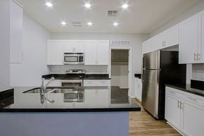 Chandler townhouse for rent - a kitchen with white cabinets and black counter tops