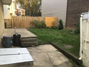 Philadelphia apartment for rent - A backyard with a wooden fence and a trash can.