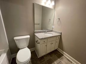 Wilson apartment for rent - A bathroom with a toilet, sink, and mirror.