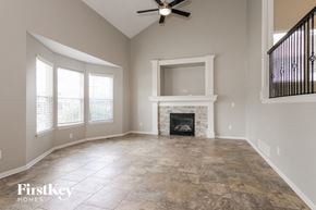 Kansas City house for rent - an empty living room with a fireplace and a ceiling fan