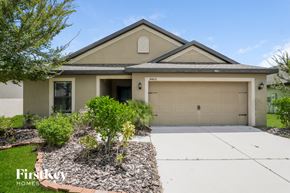 Wimauma house for rent - A house with a garage and a driveway in front of it.