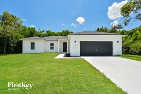 Deltona house for rent - A white house with a black garage door is for sale by FirstKey Homes.