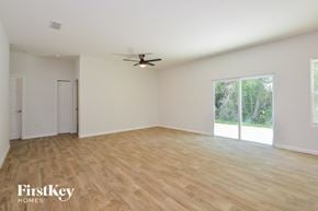 Deltona house for rent - A spacious room with a ceiling fan and wooden flooring.