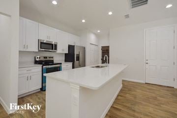 Deltona house for rent - A kitchen with white cabinets and a white island.