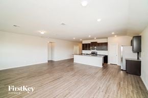 New Braunfels house for rent - A spacious living room with wooden flooring and a kitchen area in the background.