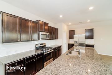 New Braunfels house for rent - A kitchen with dark brown cabinets and a granite countertop.