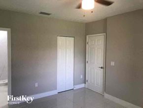Lehigh Acres house for rent - an empty living room with a door and a ceiling fan