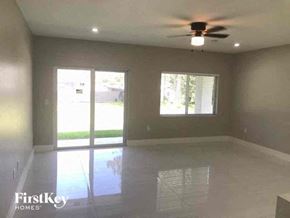 Lehigh Acres house for rent - an empty living room with a ceiling fan and a window