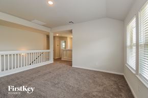Anahuac house for rent - A spacious room with a carpeted floor and a staircase with white railings.