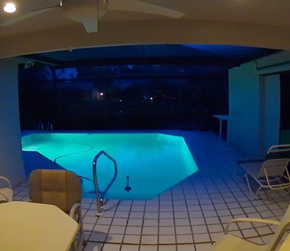 Fort Myers house for rent - a swimming pool at night in a room with chairs and tables