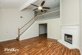 Fort Worth house for rent - A spacious living room with a fireplace and a ceiling fan.